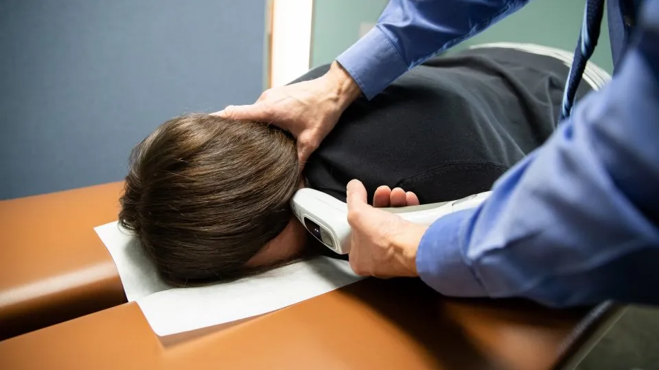 Chiropractor using the activator method on a patient's neck