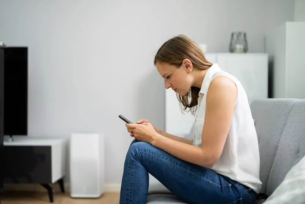 Woman leaning forward on a couch looking at her phone