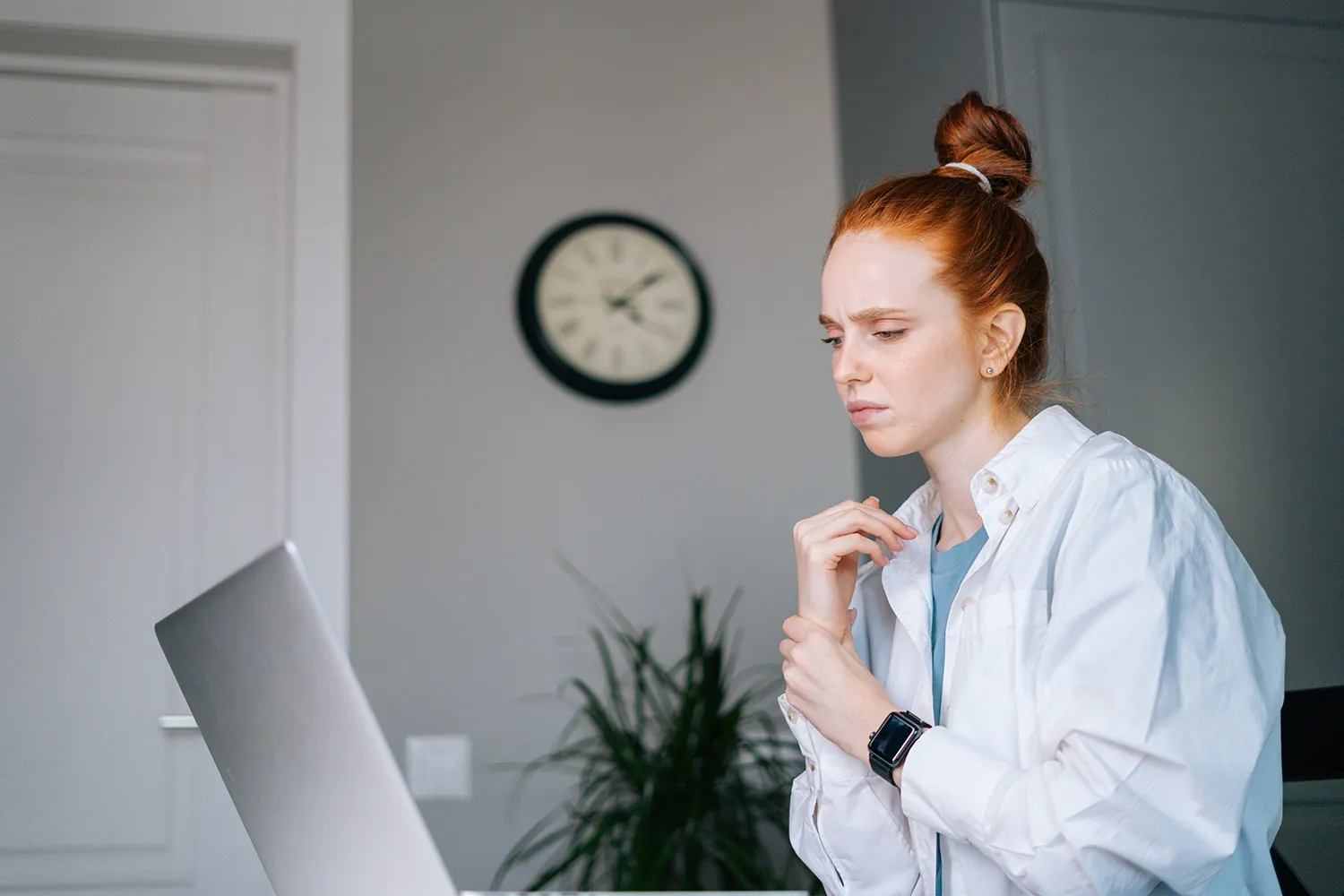 Woman working from home holding her arm due to carpal tunnel pain