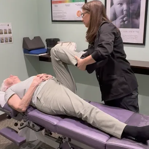 Dr. Jill Kirar adjusting a patient's knee on a chiropractic table