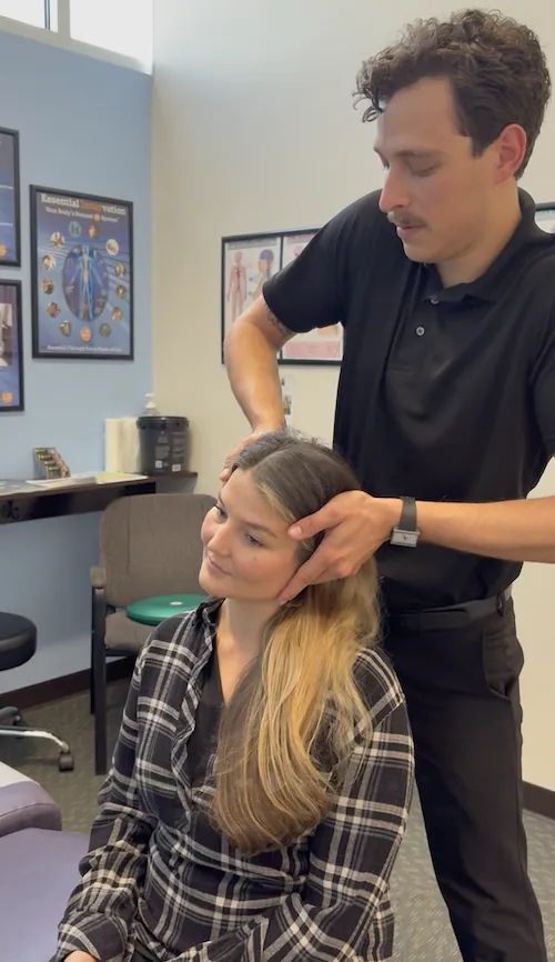 Dr. Kyle Ordille adjusting a seated patient's neck