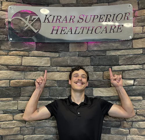 Dr. Kyle Ordille pointing at the Kirar Superior Healthcare sign