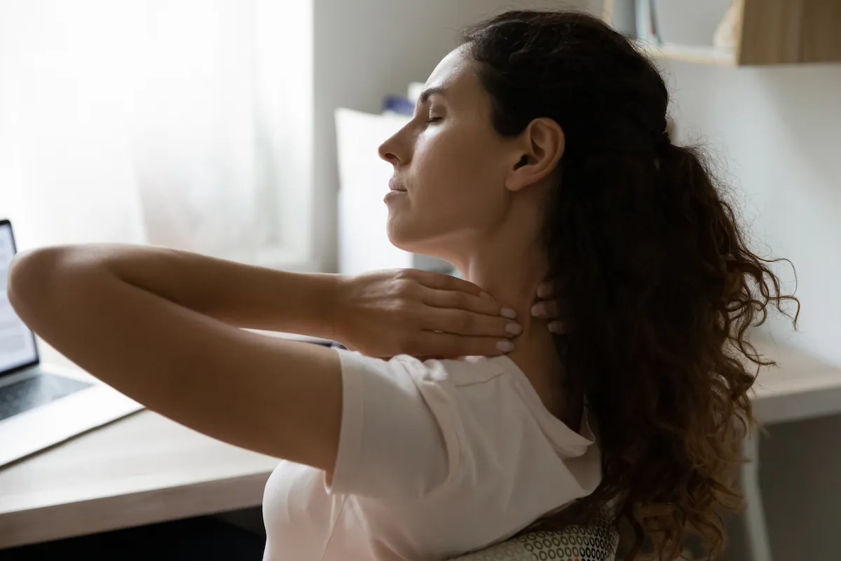 Woman at a desk massaging the side of her neck