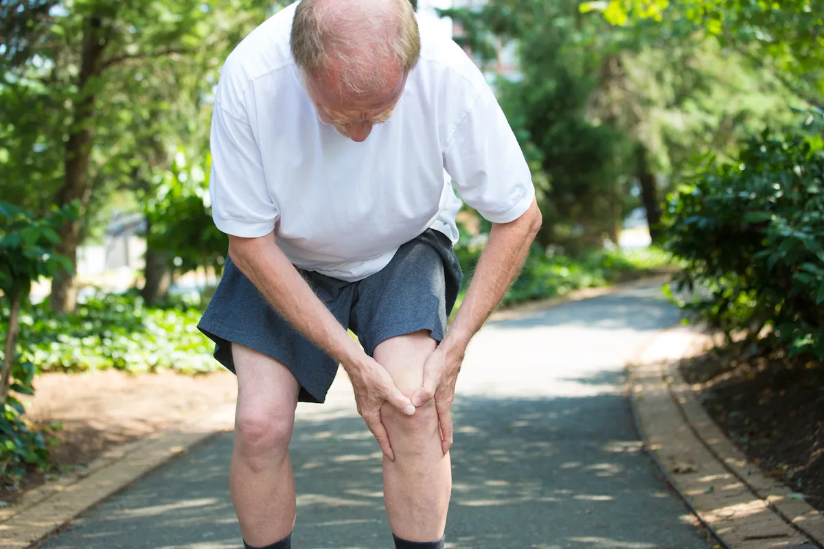 Older man walking with knee bursitis pain