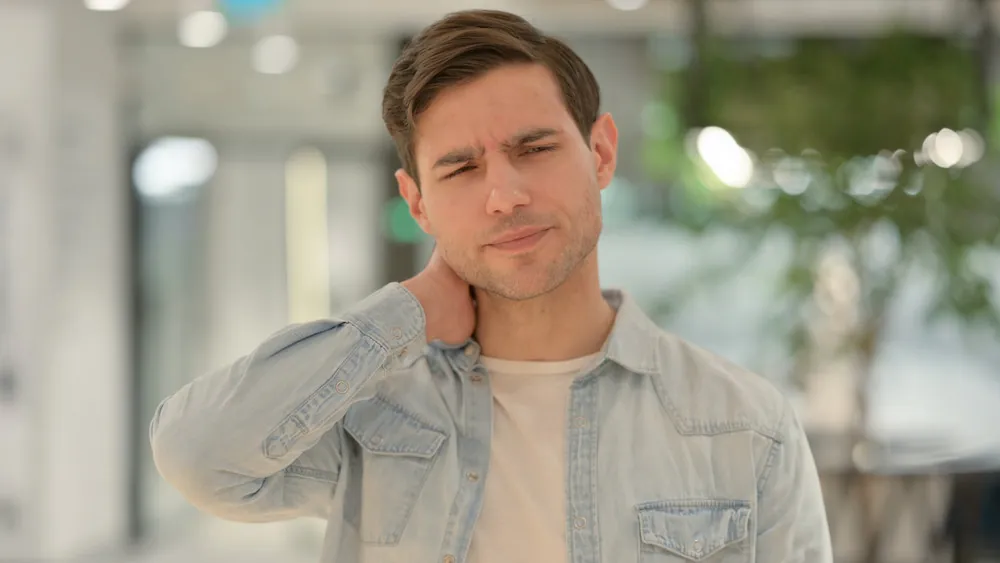 Man holding the side of his neck