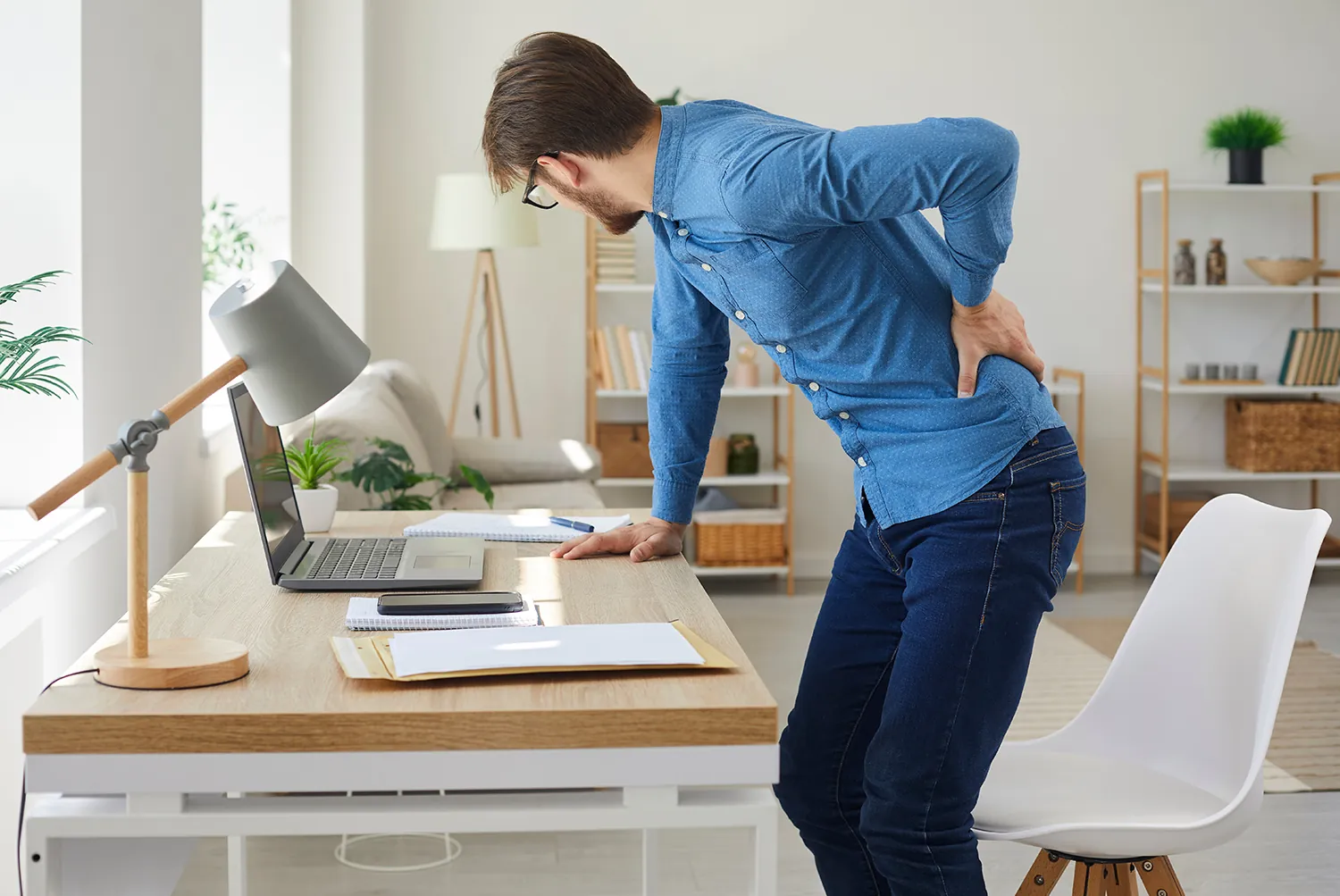 Man at a desk holding his lower back