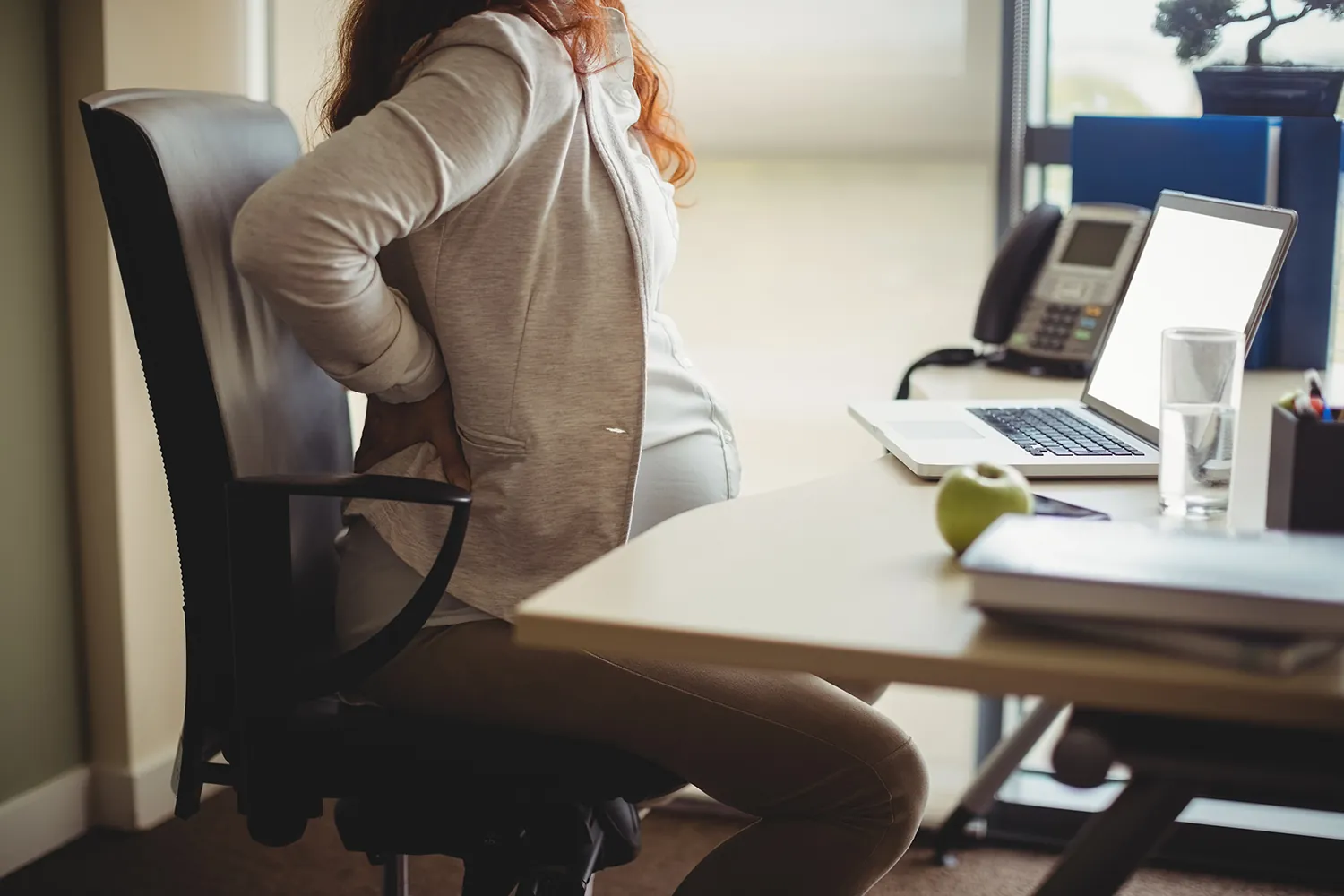 Pregnant woman working in an office with lower back pain
